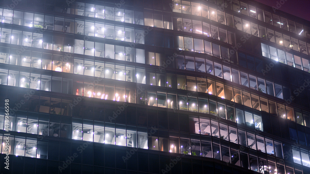 Corporate building at night - business concept. Glass wall office building .Modern office windows of skyscraper glowing at night.