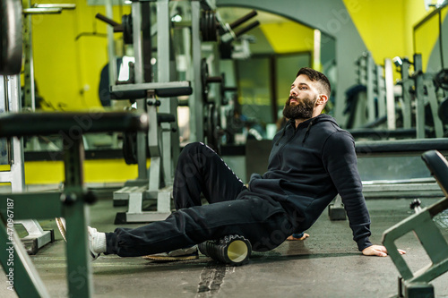 фотографія Sport man Using black Foam Roller for Muscle and Fascia Stretching leg - Male at