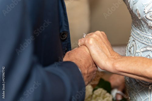 Ring finger of happily married bride proudly displays the wedding band as she holds the hand of her husband