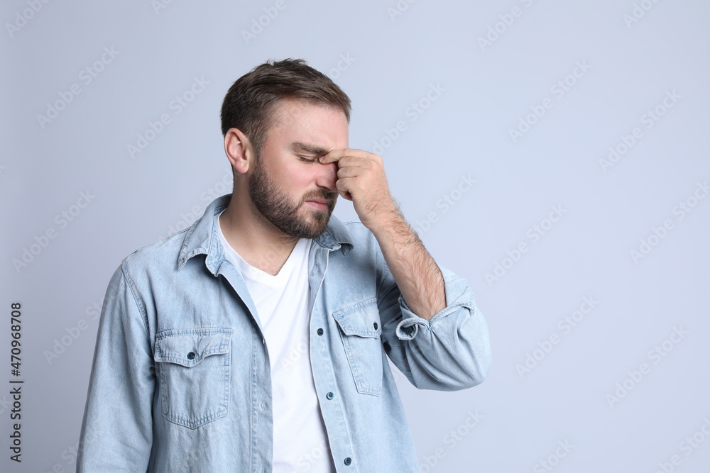 Young man suffering from headache on light background, space for text Young man suffering from headache on light background, space for text