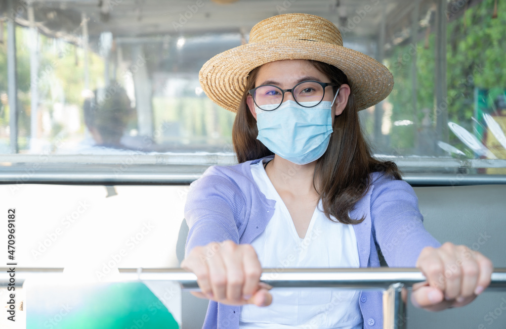 Young Asian woman wearing surgical mask for protect herself from covid-19 spreading while going outside or public space. Conceptual shot of new normal lifestyle after covid-19 pandemic.