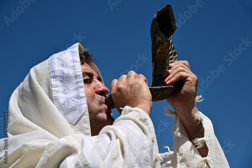 Fotografie Portrait of an orthodox adult Jewish man blow Shofar (ram's horn) outdoors under clear blue sky, on the Jewish High Holidays in Rosh Hashanah and Yom Kippur