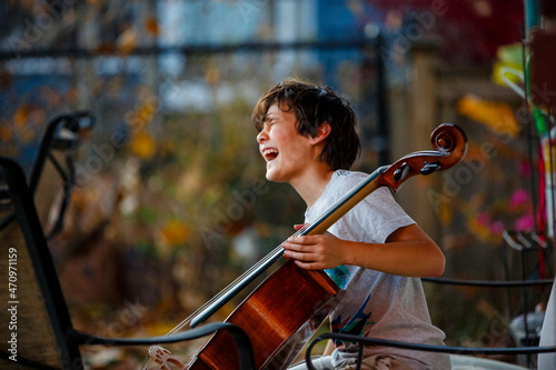 A laughing child sits outside in golden light with a cello photo
