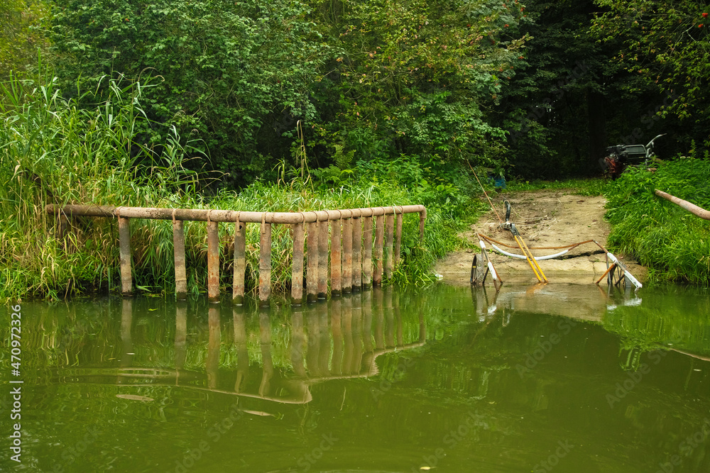 Remains of an old bridge on the river bank, summer forest landscape Remains of an old bridge on the river bank, summer forest landscape