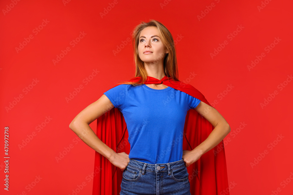 Confident woman wearing superhero cape on red background - obrazy, fototapety, plakaty 
