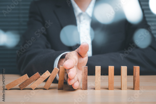 Businesswoman hand stop domino effect before destroy stack of money, Protection finance from domino effect concept.