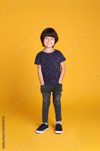 Full length portrait of cute little boy on yellow background