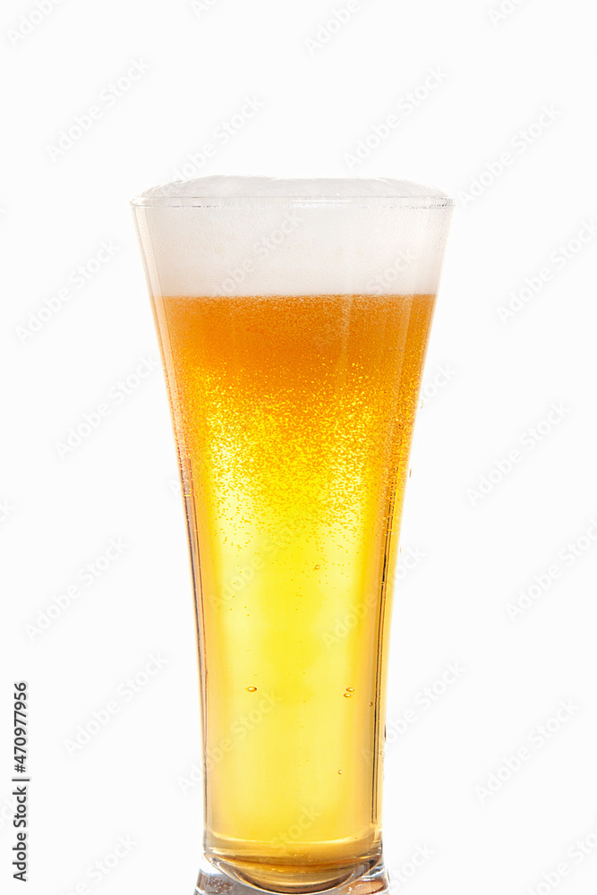 Light beer with foam in a tall transparent beer glass on a white background Light beer with foam in a tall transparent beer glass on a white background