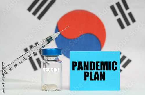 Vaccine, syringe and blue plate with the inscription - PANDEMIC PLAN. In the background the flag of South Korea