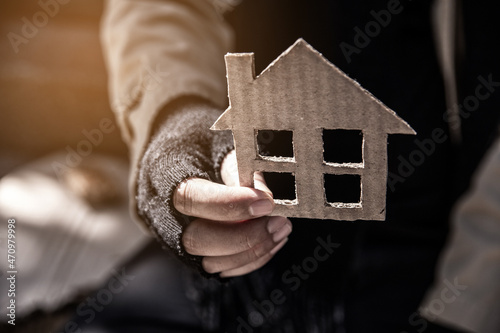dirty hand of homeless beggar with House shaped cardboard.