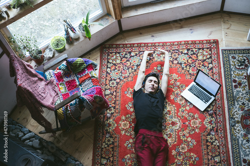 Young male freelancer resting lying on the carpet in vintage style geo dome home © Annatamila