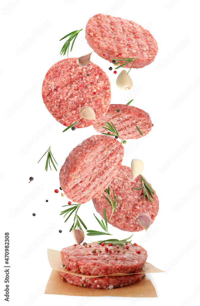 Fresh raw burger patties and seasonings falling on white background Fresh raw burger patties and seasonings falling on white background