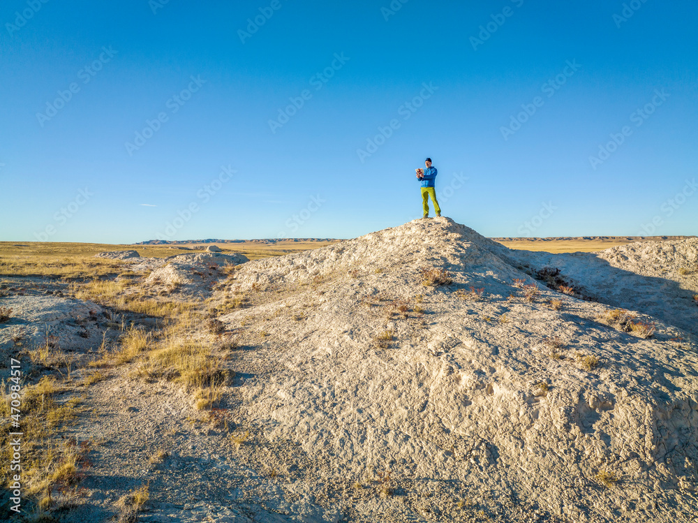 Fototapeta premium drone pilot with a tablet and radio controller at badlands in Colorado prairie, fall scenery aerial