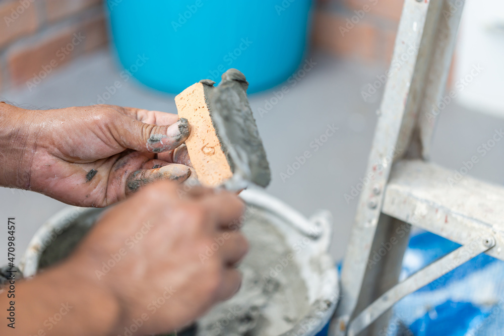 Close up hand of worker plastering cement on clay bricks, Construction bricklayer worker building walls with bricks, mortar and putty knife