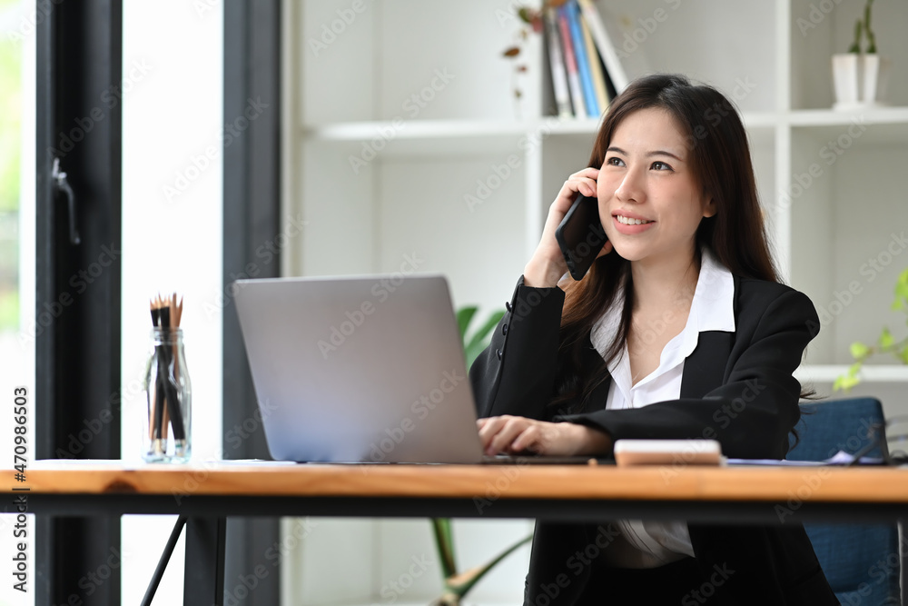 Thoughtful businesswoman talking on mobile phone and using computer laptop. Thoughtful businesswoman talking on mobile phone and using computer laptop.