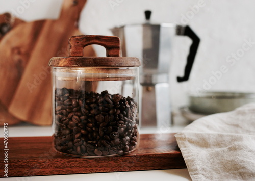 Glass jar with coffee beans, wooden kitchenware. Modern kitchen backdrop. Breackfast lifestyle. Toned.  photo