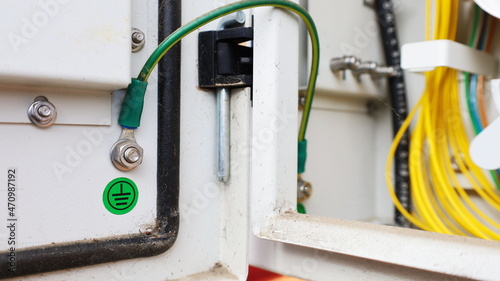 Yellow-green ground wire in a metal box. Gray metal box has a ground wire connected on the lid to prevent electric shock with a ground symbol sticker. selective focus
