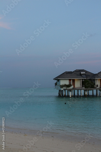 Villas on stilts above the water in the Maldives. White sand, calm Indian Ocean, blue sky. © Elena