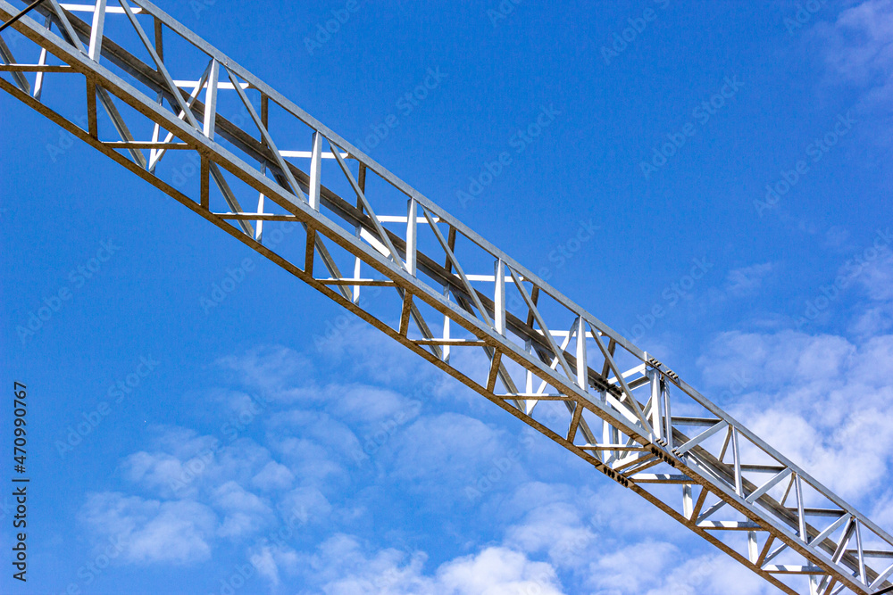 Steel truss made of metal corners against the blue sky. Structure of steel roof frame for building construction. Framework detail of metal bridge. Closeup bottom view