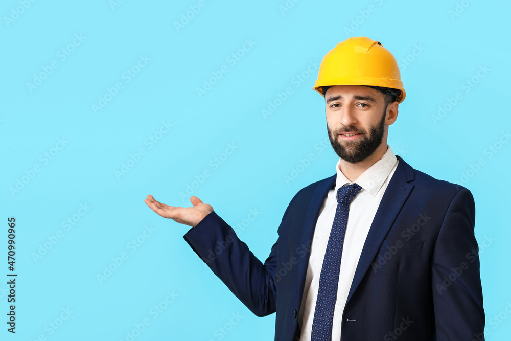 Industrial engineer in hardhat showing something on blue background Industrial engineer in hardhat showing something on blue background