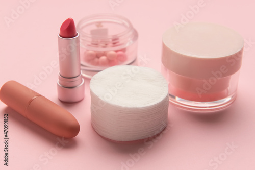Clean cotton pads, face cream and cosmetics on pink table, closeup