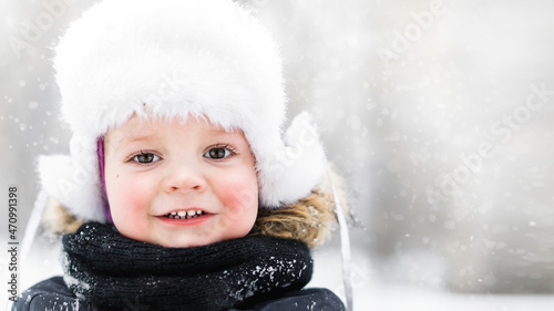 Close-up of a portrait of a small smiling child in the fresh air in winter.