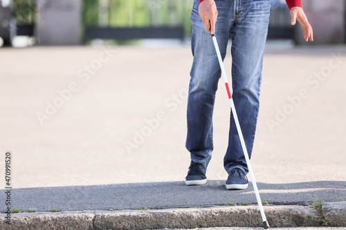 Blind senior man crossing road in city