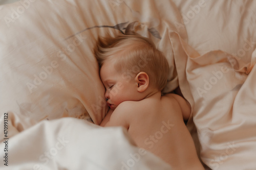 The baby sleeps sweetly in bed lying on his stomach