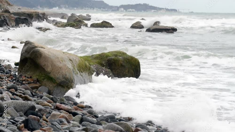 Waves breaking against shoreline of rocks an boulders Waves breaking against shoreline of rocks an boulders