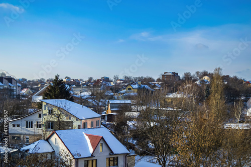 Snow-covered roofs of rural houses against the blue sky. Rural houses. Winter season. Blue sky. Cumulus clouds. White sneh. Cloudy horizon. Winter landscape. Background image. photo