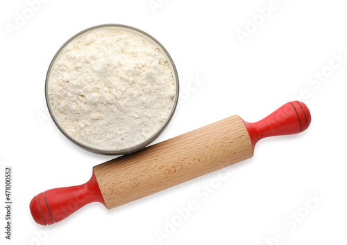 Wooden rolling pin and bowl with flour on white background, top view photo