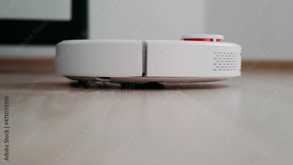 The robot vacuum cleaner cleans the floor in the room. Technologies that help housewives clean the apartment. Close-up of a vacuum cleaner driving on the floor. Housekeeping. The robot vacuum cleaner cleans the floor in the room. Technologies that help housewives clean the apartment. Close-up of a vacuum cleaner driving on the floor. Housekeeping.