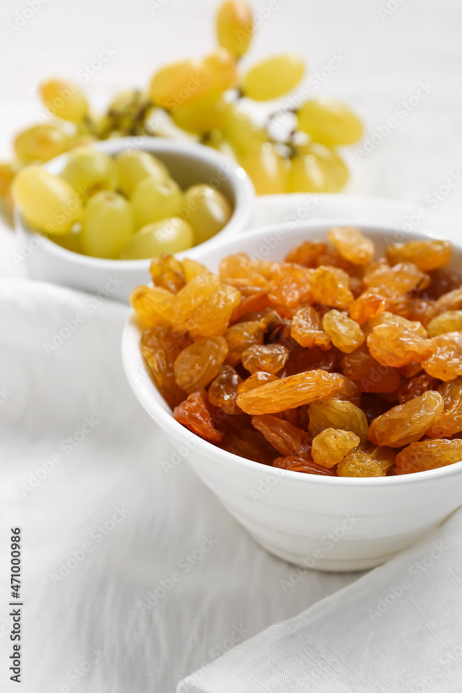 Fototapeta premium Bowl with tasty raisins on table, closeup
