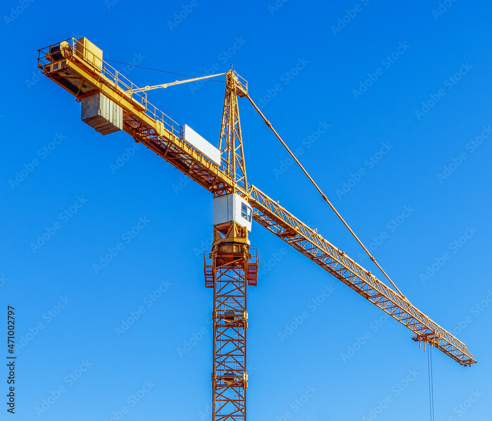 Construction tower crane against a background of blue sky Construction tower crane against a background of blue sky