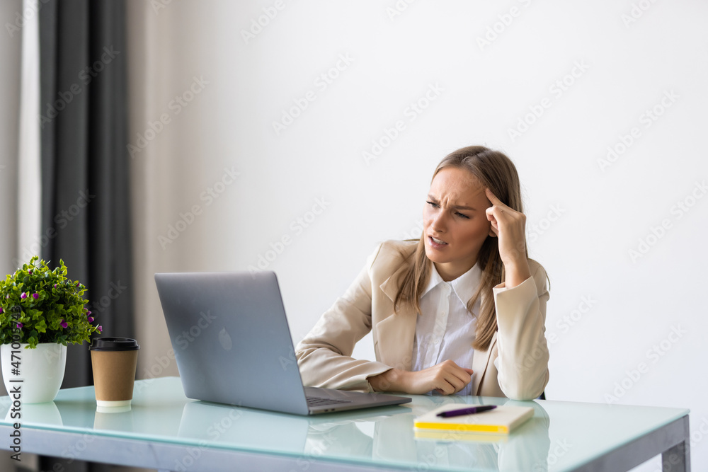 Worried young businesswoman reading a notification sitting in a desktop at office