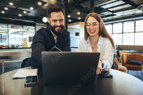 Colleagues smiling while looking at a laptop