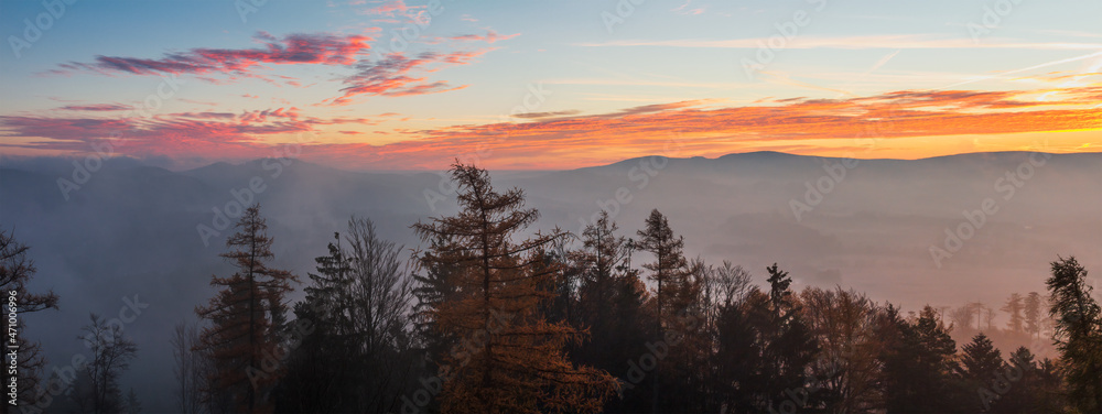 Autumn czech landscape with misty fog and trees silhouette at morning sunrise. Panoramic view from watchtower in village Hradiste