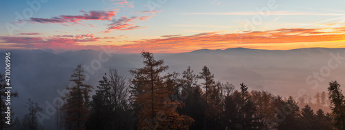 Autumn czech landscape with misty fog and trees silhouette at morning sunrise. Panoramic view from watchtower in village Hradiste