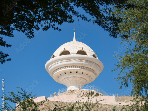 View to the Riyam Park monument dome through the palm leaves. Muscat, Oman.