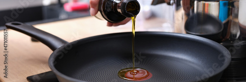 Chef pouring olive oil into frying pan in kitchen closeup photo