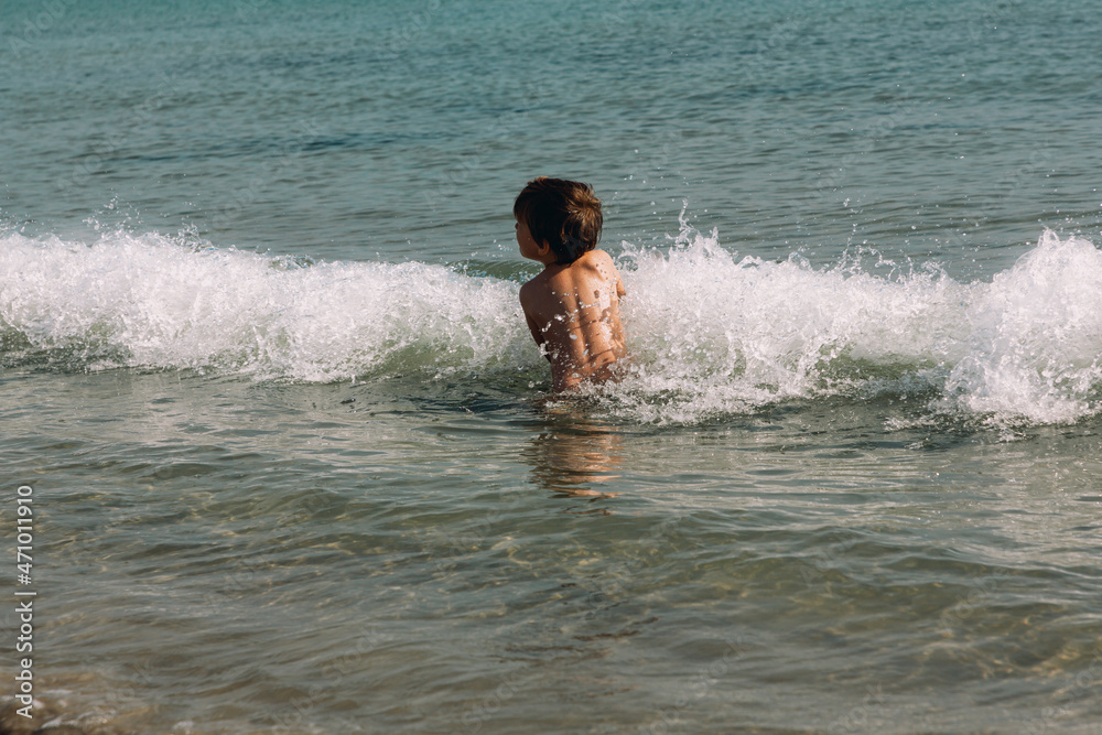 Boy plays with waves in the sea.