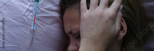 Obraz na plátně Young woman in bed and holding her head near mercury thermometer