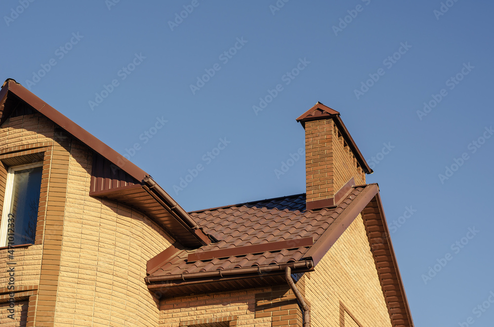The brown roof with mantel chimney of a beautiful modern stone m
