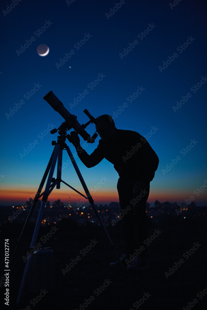 Silhouette of a man and telescope under the starry skies.