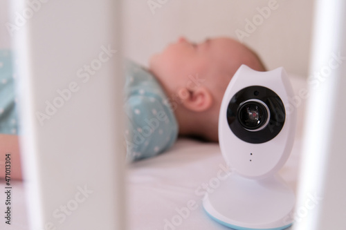 Baby monitor camera watching over a Caucasian baby while he sleeps in the crib. photo