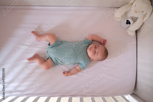 Baby monitor camera watching over a Caucasian baby while he sleeps in the crib.