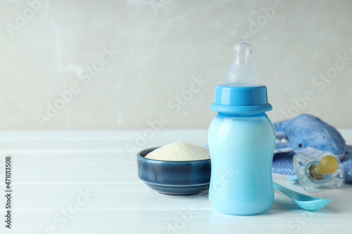 Concept of baby food with рowdered milk on white wooden table