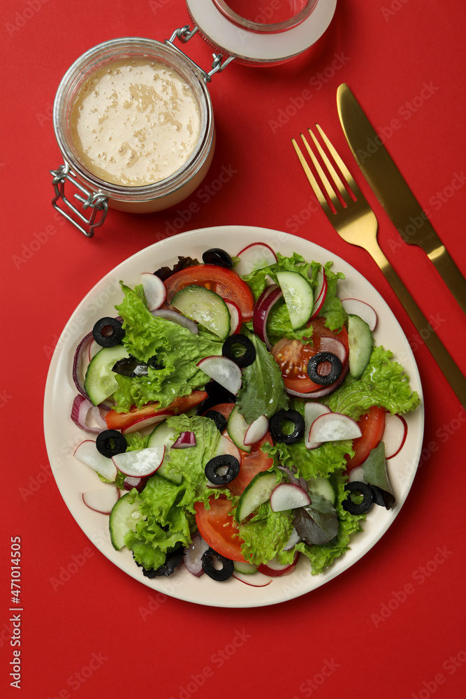Concept of tasty food with vegetable salad with tahini sauce on red background