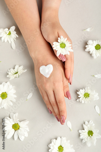 Concept of hand care on gray background with flowers