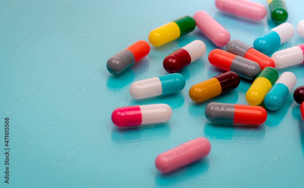 Antibiotic capsule pills on blue background. Prescription drugs. Colorful capsule pills. Antibiotic drug resistance concept. Pharmaceutical industry. Superbug problems. Medicament and pharmacology.